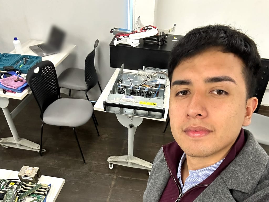 Laboratorio técnico con un servidor abierto, una placa base y herramientas sobre las mesas de trabajo